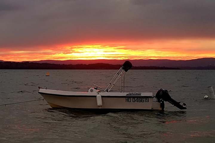a small boat in a body of water with a sunset in the background