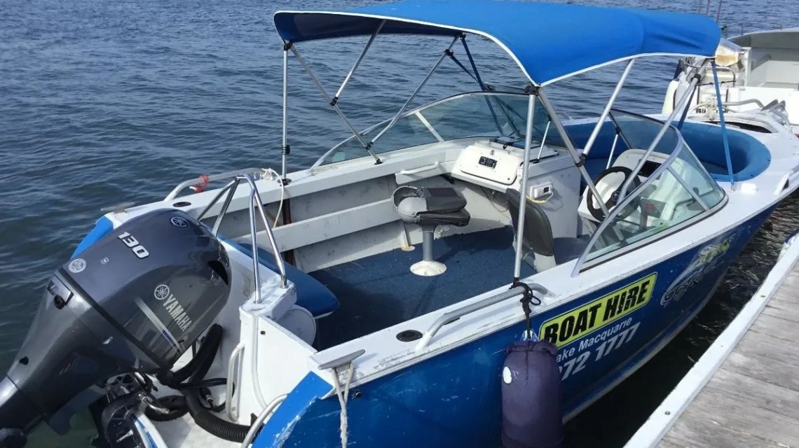 4-Hour-Bowrider-Sports-Boat-Hire-image-1 a blue and white boat sitting next to a body of water