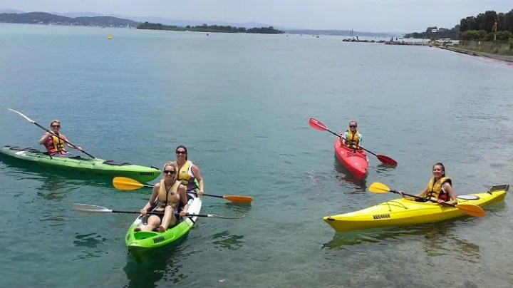 Kayaking a group of people riding on the back of a boat in the water